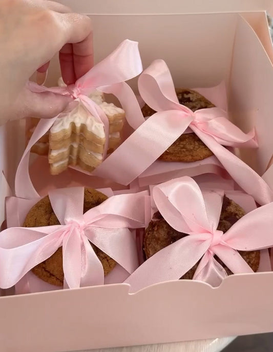 Box of cookies with pink ribbons being held by a hand